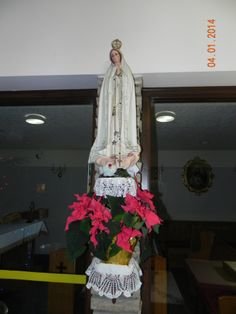 a statue of the virgin mary on top of a vase with poinsettis