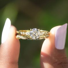 a woman's hand holding an engagement ring with two stones on the front and side