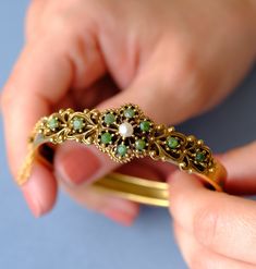 This is a beautiful gold-plated (vergoldet) bangle, created around the 1940s. The bangle features intricate detailing with a central floral motif. It is adorned with 10 jade stones and a central pearl. The design is reminiscent of the Victorian era. The bottom half of the bangle is plain, free of design. The bangle can be easily opened and closed with a box clasp, and an additional safety chain ensures it is secure and easy to put on and take off. Condition: Excellent vintage condition, with all Vintage Yellow Gold Cuff Bracelet With Intricate Design, Gold Victorian Cuff Bracelet With Intricate Design, Antique Yellow Gold Cuff Bangle Bracelet, Victorian Cuff Bracelet With Intricate Design, Antique Gold Bangle Bracelet For Ceremonies, Antique Gold Bangle Bracelet For Ceremonial Occasions, Vintage Yellow Gold Bangle, Antique Gold Cuff Bracelet With 17 Jewels, Gold Victorian Bangle With Intricate Design