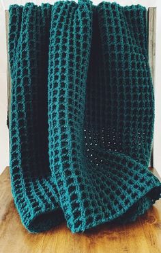 a green crocheted blanket sitting on top of a wooden table