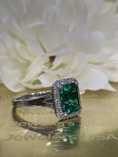 This ring is an emerald cut lab created green emerald with genuine diamond halo made with solid 14k white gold item #5457 We feature the finest quality lab grown emeralds in the world. The properties of lab-grown are physically, chemically and visually identical to natural, just grown in a lab setting. Emerald is the birthstone of May -Approximate total carat weight: 2.75ctw diamond equivalent -Center Stone Size: approx. 2.50ct diamond equivalent -Center Stone Shape: emerald cut 9x7mm -Gem Type: 14k White Gold Emerald Ring With Brilliant Cut, Emerald Cut Green Diamond Ring With Prong Setting, Green Diamond Ring With Radiant Cut And Prong Setting, Green Emerald-cut Ring With Halo Design, Green Emerald Cut Ring With Halo Design, 14k White Gold Emerald Cut Halo Ring, Green Emerald Diamond Ring With Halo, Emerald Cut Emerald Ring With Halo Setting, Radiant Cut Emerald Diamond Ring With Center Stone