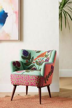 a colorful chair sitting in front of a painting on the wall next to a potted plant