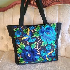 This gorgeous floral tote can easily go from casual to dressy. Colorful embroidered flowers and birds are featured on the front panel of the sturdy canvas bag with ample room to hold all of your everyday items. Approx. 13.5" X 17" bag with 12" handles Machine embroidered Canvas Material Fully lined with small pocket Zipper closure Floral Embroidered Canvas Tote Bag For Everyday Use, Blue Embroidered Bag For Daily Use, Floral Embroidered Canvas Shoulder Bag For Everyday Use, Blue Bags With Floral Embroidery For Daily Use, Daily Use Blue Bags With Floral Embroidery, Blue Embroidered Canvas Bags, Embroidered Blue Rectangular Shoulder Bag, Cotton Shoulder Bag With Floral Embroidery, Embroidered Blue Bag