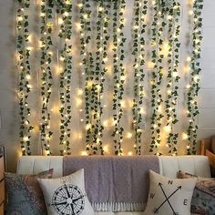 a living room filled with lots of pillows and lights hanging from the wall above it