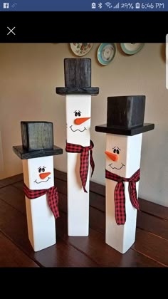 three snowmen with hats and scarfs are standing in front of each other on a table