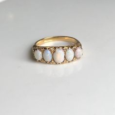 A stunning vintage 18 carat yellow gold five-stone ring set with five oval cut Opals and diamonds. These opals are beautiful and display every colour from blues and greens to reds and oranges. CONDITION: Good condition. A chip to middle Opal. Please see photos for more detail. OPAL SIZE (LARGEST): 5mm x 7mm (0.75ct) DIAMOND SIZE: 1mm (0.01 carat) OVERALL SETTING SIZE: 8mm x 22mm RING SIZE: UK: Q | US: 8 1/4 WEIGHT: 6.1 grams (DHZ) Heirloom Oval Opal Ring For Anniversary, Classic White Cabochon Opal Ring, Classic Oval Hallmarked Opal Ring, Antique Multi-stone Opal Ring For Anniversary, Heirloom Oval Opal Ring Hallmarked, Classic Multi-stone Opal Ring For Formal Occasions, Victorian Oval Opal Ring Hallmarked, Classic Opal Anniversary Ring, Victorian Style Oval Opal Ring With Hallmark