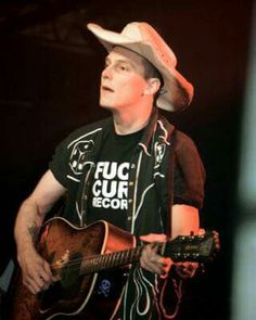 a man wearing a cowboy hat playing a guitar