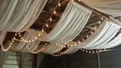 a room filled with lots of white drapes and string lights hanging from the ceiling