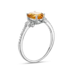 a ring with an oval cut citrine and diamonds on the sides, set in white gold