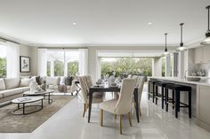 a living room filled with furniture next to a kitchen and dining room table in front of a large window