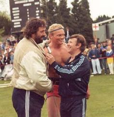 two men standing next to each other in front of a crowd at a sporting event