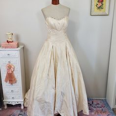 a dress on display in front of a white dresser and pink carpeted flooring