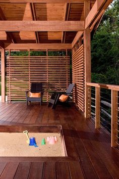 a wooden deck with chairs and sandbox in the middle on it's side