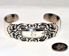 "This is a vintage Towle sterling silver cuff bracelet in the Grand Duchess pattern with a monogram E. The bracelet has a 7.5\" circumference or 2.5\" in diameter with a 1.5\" gap in the back, weighs 46.1 grams on my scale and is in excellent condition. My wrist is 7\" and this fits nicely with room to spare. The bracelet will be gently cleaned with a jewelers cloth before before being sent, gift box included. Vintage dime not included." Vintage Stamped Cuff Bracelet For Wedding, Antique Stamped Cuff Bracelet For Formal Occasions, Vintage Sterling Silver Bracelet For Anniversary, Silver Stamped Cuff Bracelet For Wedding, Classic Silver Stamped Bracelets, Classic Engraved Cuff Bracelets, Victorian Engraved Cuff Bracelet For Anniversary, Classic Engraved Cuff Bracelet, Vintage Bangle Jewelry With Engraving Option