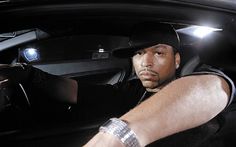 a man sitting in the driver's seat of a car with his hand on the steering wheel