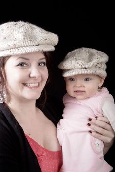 a woman holding a baby in her arms and wearing knitted hats on their heads