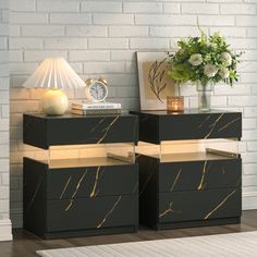 two black and gold nightstands sitting next to each other in front of a white brick wall