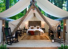 a bed sitting in the middle of a bedroom covered in white drapes and curtains