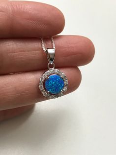 "Blue Opal Halo Necklace Minimalist and Dainty Necklace Metal: All components are made from solid .925 Sterling Silver Stone: 8mm Lab Created Opal; Cubic Zirconia Measurement: Pendant Height is 19mm (0.75\") including bail and 13mm (0.51\") wide Choose Chain Length Please feel free to Convo me with any questions before purchasing. Please view policy before purchasing Other Opal Necklaces can be found here https://www.etsy.com/shop/LinksAndStones?ref=ss_profile&section_id=24284450 Thank You F Round Pendant Necklace With Halo Setting Gift, Halo Round Pendant Necklace As Gift, Halo Round Pendant Necklace For Gift, Blue Necklace With Halo Setting For Gift, Halo Round Pendant Jewelry For Gift, Sterling Silver Halo Jewelry, Halo Round Pendant Jewelry Gift, Sterling Silver Halo Round Cut Jewelry, Minimalist Silver Jewelry With Halo Design