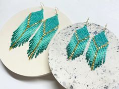 two pairs of turquoise beaded earrings sitting on top of a white plate next to each other