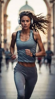 a woman wearing headphones running down a street with her hair blowing in the wind