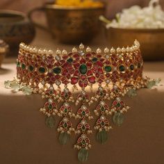 a red and green choker with pearls on the neck, surrounded by other jewelry items