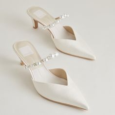 a pair of white shoes with pearls on the toe and heel, sitting next to each other