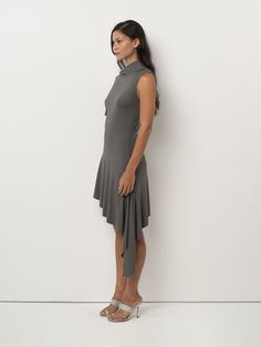 The Plume Dress features a mock neckline, asymmetrical waterfall shoulder, and asymmetrical flounced hemline. Chic Fitted High Low Dress With Asymmetrical Hem, Fitted Asymmetrical Ruffle Dress, Fitted Asymmetrical Dress With Asymmetrical Hem, Elegant Asymmetrical Ruffle Dress With High-low Hem, Asymmetrical Stretch Dress With Ruffles, Asymmetrical Mini Dress With Ruffle Hem, Evening Asymmetrical Dress With Ruffle Hem, Elegant Asymmetrical Mini Dress With Ruffle Hem, Evening Dresses With Ruffle And Asymmetrical Hem