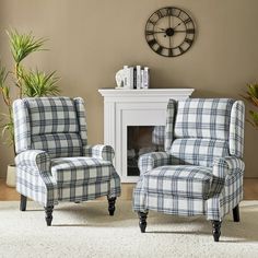 two plaid chairs in front of a fireplace with a clock on the wall behind them