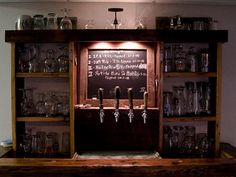 an old fashioned bar with lots of glasses on the shelf and chalkboard behind it