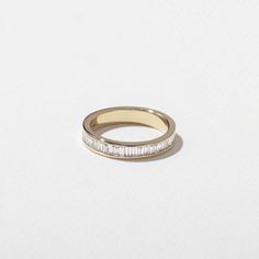 a yellow gold band with baguettes on the side, set against a white background