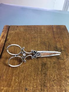 a pair of scissors sitting on top of a wooden table