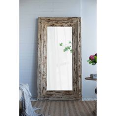 a large mirror sitting on top of a wooden floor next to a white brick wall