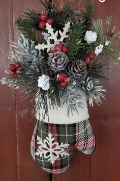 a christmas stocking hanging on the side of a wooden door with snowflakes and evergreens