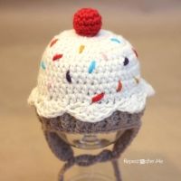 a crocheted hat with a red pom - pom sitting on top of it