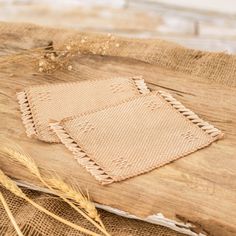 two pieces of cloth sitting on top of a piece of burlied fabric next to some wheat stalks