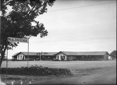 an old black and white photo of a street sign in front of a school building