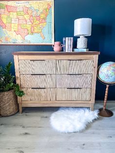 a wooden dresser sitting next to a blue wall with a map on top of it