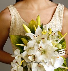 a woman holding a bouquet of white flowers in her hand and wearing a wedding dress