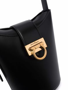 Trifolio bucket bag from SALVATORE FERRAGAMO featuring black, calf leather, engraved logo, gold-tone hardware, buckle fastening, foldover top and adjustable shoulder strap. Size Info UNI Color Detail Black Made In Italy Material Calf Leather 100% Season One Fall-Winter Season Two Fall-Winter Product bags.. Brand Ferragamo Size And Fit Width 11,81 in / 30 cm Height 7,48 in / 19 cm Depth 3,94 in / 10 cm Handle 11,81 in / 30 cm Leather Engraved, Black Bucket Bag, Ferragamo Bag, Salvatore Ferragamo Bags, Leather Engraving, Black Bucket, Crossbody Tote Bag, Leather Bucket Bag, Leather Bucket