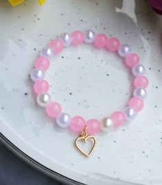 Introducing Our "Blushing Hearts" Bracelet: A Touch of Romance! Embrace the enchanting allure of our heart charm bracelet, adorned with delicate pink glass beads and faux pearls. With a diameter of 15.5 cm and the flexibility to stretch to 17.5 cm, it offers a comfortable fit for wrists of various sizes. Crafted with high-quality materials, including glass beads and ABS, this bracelet exudes elegance and charm. Perfect for adding a touch of romance to any outfit or as a heartfelt gift for someon Pearl Beads Bracelet Ideas, Heart Bracelet With Round Beads As Gift, Elegant Heart-shaped Bracelets With Colorful Beads, Gift Heart Bracelet With Colorful Round Beads, Heart Beaded Bracelets For Mother's Day, Heart-shaped Beads For Valentine's Day Gift, Mother's Day Beaded Bracelets With Heart Beads, Heart-shaped Beads For Gift, Heart-shaped Beaded Pearl Bracelet Gift