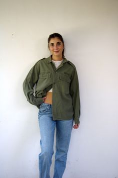 This awesome vintage green military shirt/jacket is nicely broken in, and features a button-up design with pockets. Made from cotton, it includes ventilation openings under the arms. Unisex and suitable for both men and women, aside from minor signs of wear, good vintage condition, clean ready to wear, this piece is a versatile and stylish addition to any wardrobe. ** Model is 5'7" and size S for reference **      Approximate size:  M/L- please refer to the measurements. M E A S U R E M E N T S -were taken with garments laying flat, please double where necessary. ------------------------♥-------- Length:  27"-69cm Armpit to Armpit: 23"-59cm (closed) Shoulder to Shoulder: 19.5" - 50cm Sleeve: 22.5"- 57cm. ---------------------------------------------- All items are vintage pieces, previousl Vintage Relaxed Fit Button-up Shacket, Green Collared Utility Jacket With Button Closure, Green Cotton Button-up Utility Jacket, Green Tops With Flap Pockets For Fall, Green Fall Tops With Flap Pockets, Olive Military Style Tops For Fall, Khaki Collared Tops With Cargo Pockets, Vintage Shacket With Relaxed Fit And Long Sleeves, Vintage Long Sleeve Shacket With Relaxed Fit