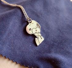 a small silver elephant charm on a blue cloth with a chain hanging from it's neck