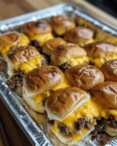 some hamburger sliders are sitting on top of tin foil and ready to be eaten