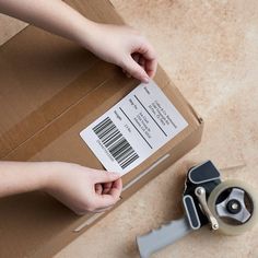 a person holding a pair of scissors next to a box with a barcode on it