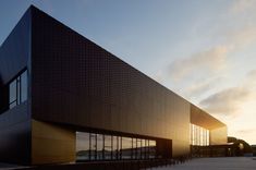 the building is made up of black bricks and has large windows on each side that overlooks water