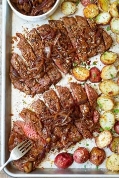 steak and potatoes on a baking sheet with a fork