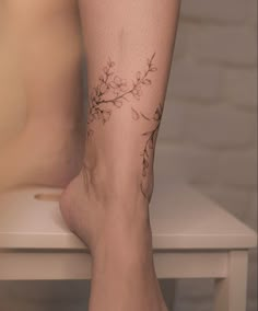 a woman's legs with tattoos on them and flowers on the bottom part of her leg