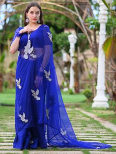 This is a three-piece midnight blue bird saree set from the Ensembles collection. The midnight blue bird saree is paired with a midnight blue blouse. There is beautiful bird motifs of shimmer cutdana work all over the saree. This saree set is crafted in semi pure organza fabric. The outfit is completed with a heavily embellished, cutdana work shimmer bird shape handbag. Traditional Blue Sets With Sheer Dupatta, Blue Sets With Sheer Dupatta In Traditional Drape, Blue Traditional Drape Sets With Sheer Dupatta, Blue Palazzo Set With Sheer Dupatta For Reception, Blue Palazzo Saree Set For Wedding, Wedding Blue Palazzo Set In Saree Style, Blue Floor-length Pre-draped Saree With Mirror Work, Blue Palazzo Set With Unstitched Blouse For Diwali, Blue Pre-draped Saree With Mirror Work