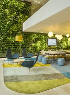 an instagram photo of a living room with green plants on the wall and blue chairs